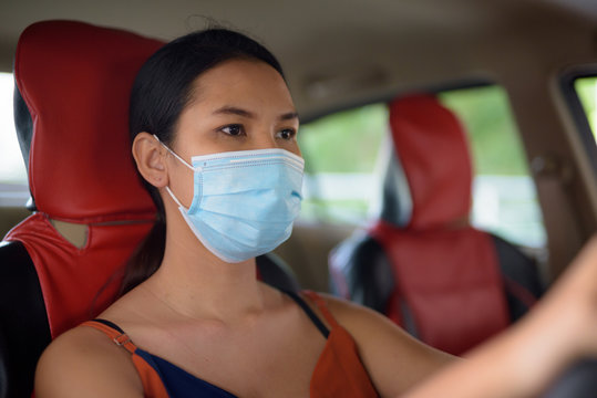 Young Asian woman wearing mask for protection from corona virus outbreak while driving the car