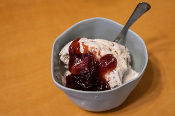 white vanilla ice cream with jam in a cup with a spoon