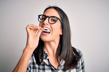 Young caucasian woman wearing glasses brushing her teeth using tooth brush and oral paste, cleaning teeth and tongue as healthy health care morning routine