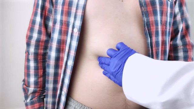 A man grabs his right side under the ribs. Pain in the liver. Pain syndrome in liver disease.