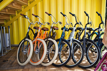 a lot of colored bikes model chopper in the city next to the yellow building in summer
