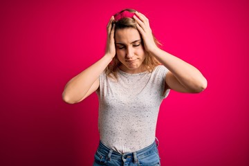 Young beautiful blonde woman wearing casual t-shirt standing over isolated pink background suffering from headache desperate and stressed because pain and migraine. Hands on head.