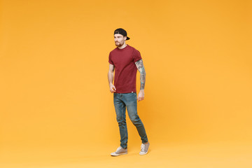 Fototapeta na wymiar Handsome young tattooed man guy in casual t-shirt black cap posing isolated on yellow wall background studio portrait. People sincere emotions lifestyle concept. Mock up copy space. Looking aside.