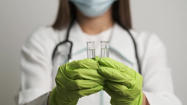 Girl doctor in a mask and gloves holds test tubes. Health, medical