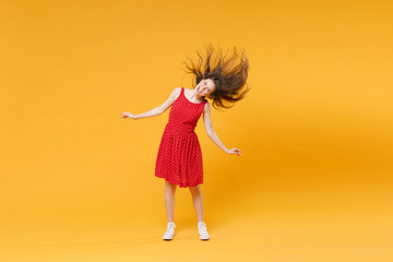 Cheerful young brunette woman girl in red summer dress posing isolated on yellow background studio...
