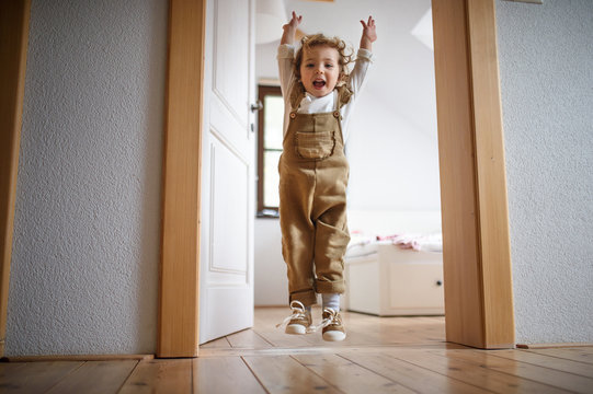 Small toddler girl jumping indoors at home, having fun.