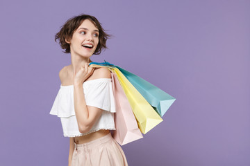 Side view of cheerful young woman girl in summer clothes hold package bag with purchases isolated...