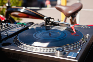 vinyl player next to the red bike on the street in the summer in the city