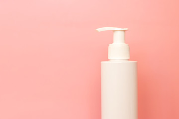White plastic bottle of skin care on pink background with copy space.