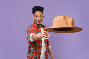 Smiling young african american guy in casual colorful shirt posing isolated on violet wall...