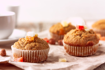 Freshly baked banana muffins with candied fruit lay on recycled paper on wooden table. Morning breakfast concept