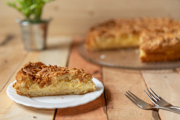 gebackener Bienenstich als Torte mit Füllung aus Creme auf Tisch aus Holz