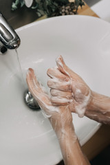 Washing hand with soap, thorough cleaning to prevent coronavirus infection, in a stylish bathroom with a white sink, top view