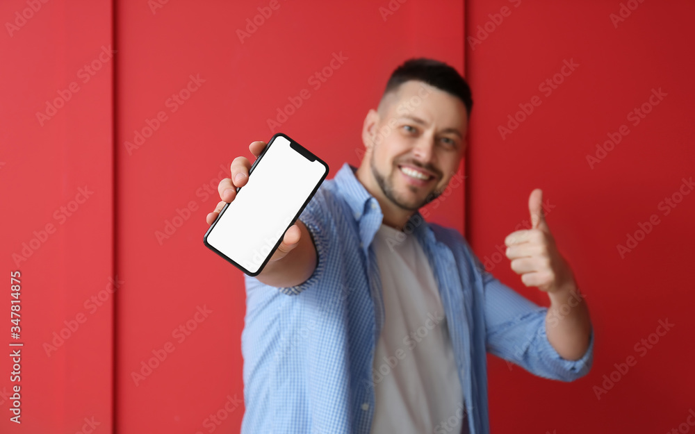 Poster handsome man with mobile phone showing thumb-up on color background