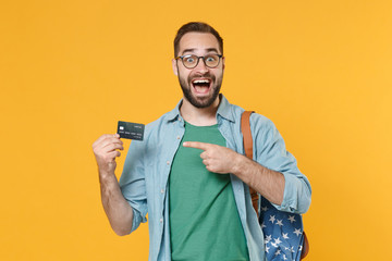 Excited young man student in casual clothes glasses with backpack isolated on yellow background...