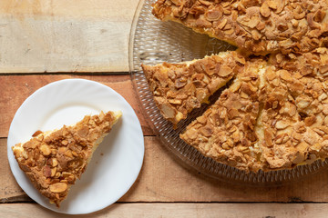 gebackener Bienenstich als Torte mit Füllung aus Creme auf Tisch aus Holz