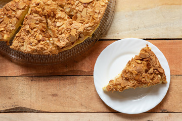 gebackener Bienenstich als Torte mit Füllung aus Creme auf Tisch aus Holz