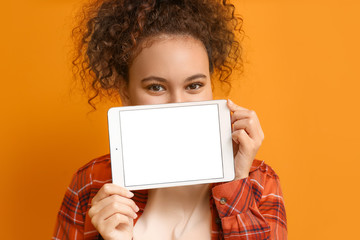 Naklejka premium Beautiful young African-American woman with tablet computer on color background