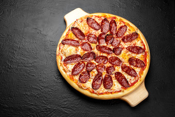 PEPPERONI pizza on a black background, tomato-based with mozzarella and spicy salami Napoli.