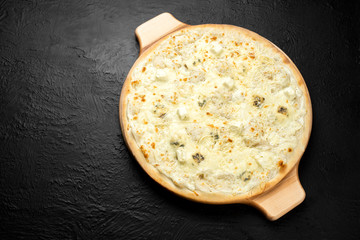 Pizza FOUR CHEESES on a black background, cream-based with mozzarella, Dor blue, Parmesan and feta cheese