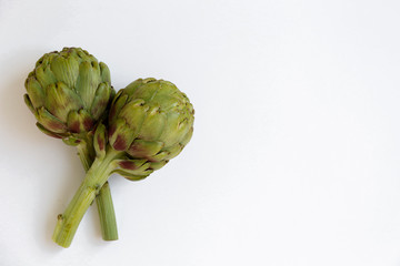 Fresh green Italian Artichoke isolated on white background. Organic local produce vegetable on table top. Vegan diet. Clean eating concept. Close up, top view, flat lay.