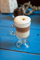 Latte in a clear glass on a blue wooden background