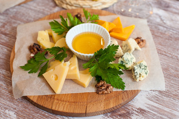 Still life cheese dish with nuts and honey on a wooden Board
