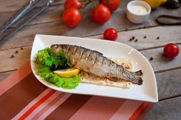 Grilled trout fish with spices, herbs and lemon fried on a grill on a white plate, top view