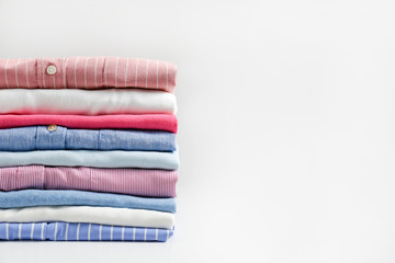 Stack of colorful perfectly folded clothing items. Pile of different pastel color shirts, sweaters...