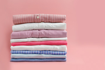 Stack of colorful perfectly folded clothing items. Pile of different pastel color shirts and...