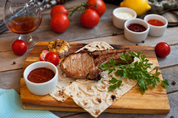 Steak on the bone. Steak on a wooden Board with vegetables and herbs. The view from the top.