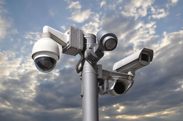 CCTV cameras on one mast against a blue cloudy sky.