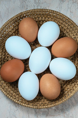 several fresh chicken eggs in a straw basket on a wooden background. Healthy eating concept.