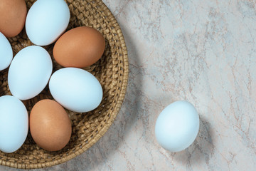 several fresh chicken eggs in a straw basket on a wooden background. Healthy eating concept.