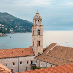 Fototapeta na wymiar view of the watchtower and tiled roofs of the ancient Croatian city of Dubrovnik against the background of the sea and cloudy sky