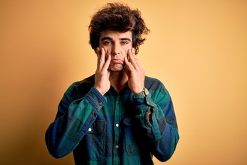 Young handsome man wearing casual shirt standing over isolated yellow background Tired hands covering face, depression and sadness, upset and irritated for problem