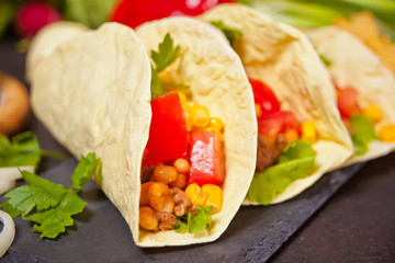 Mexican tacos with chicken meat, beans, tomatoes and corn