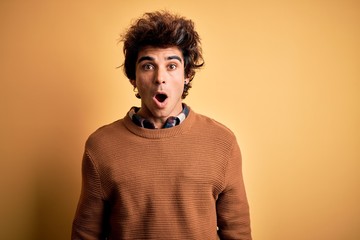 Fototapeta na wymiar Young handsome man wearing casual shirt and sweater over isolated yellow background afraid and shocked with surprise and amazed expression, fear and excited face.