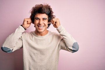 Young handsome man wearing casual t-shirt standing over isolated pink background Smiling pulling ears with fingers, funny gesture. Audition problem