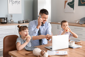 Little children keeping father from his work at home
