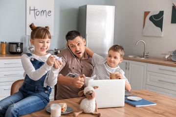 Little children keeping father from his work at home