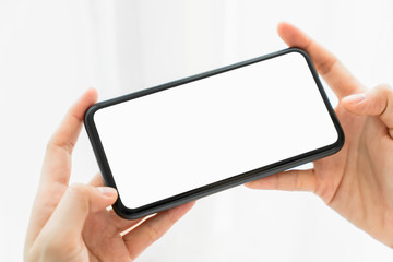 Hand holding smartphone mockup of blank screen on the table. Take your screen to put on advertising.