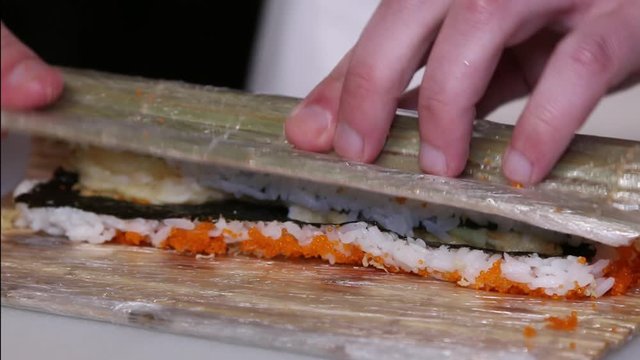 Chef's hands rolling a sushi roll. Sushi making process. Rolls the sushi roll	
