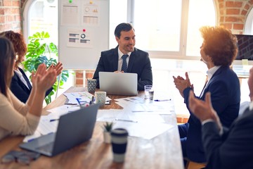 Group of business workers smiling happy and confident in a meeting. Working together looking at presentation using board and laptop applauding at the office.