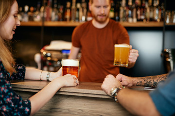 Young ginger barman serving beer to his customers.