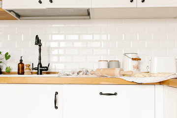 White kitchen view with rooling pin and uncooked homemade dumplings with potatoes on wooden countertop.