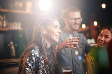 Group of friends drinking beer, chatting and having gun at pub.