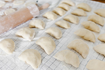 Raw uncooked homemade dumplings with potatoes and onions on wooden table in the kitchen.