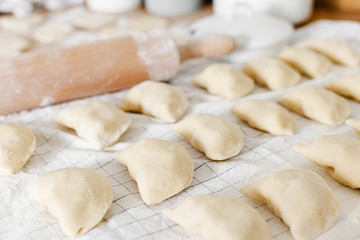 Raw uncooked homemade dumplings with potatoes and onions on wooden table in the kitchen.