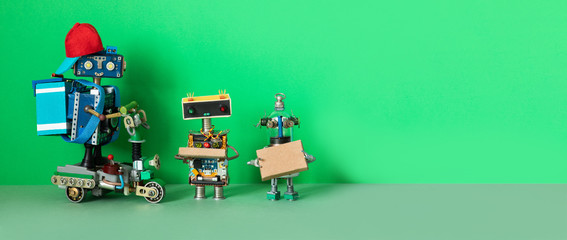 A robot courier delivered orders parcels to buyers. Two robots are holding cardboard boxes with...